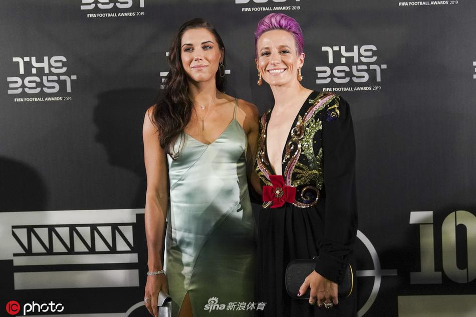 在舞台的绚丽背景下，拉皮诺埃与她的美国女足队友兼竞争对手亚历克斯·摩根同框，两人脸上洋溢着自豪的笑容，共同庆祝这个属于美国女足的辉煌夜晚。