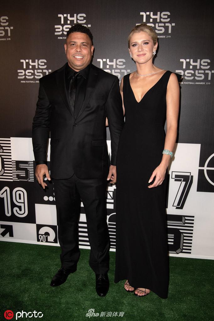 镜头拉近，大罗眼神坚定而温和，身旁的女伴侧身望向镜头，礼服上的珠饰在灯光下闪烁，背景虚化的光影衬托出这对组合的星光熠熠。