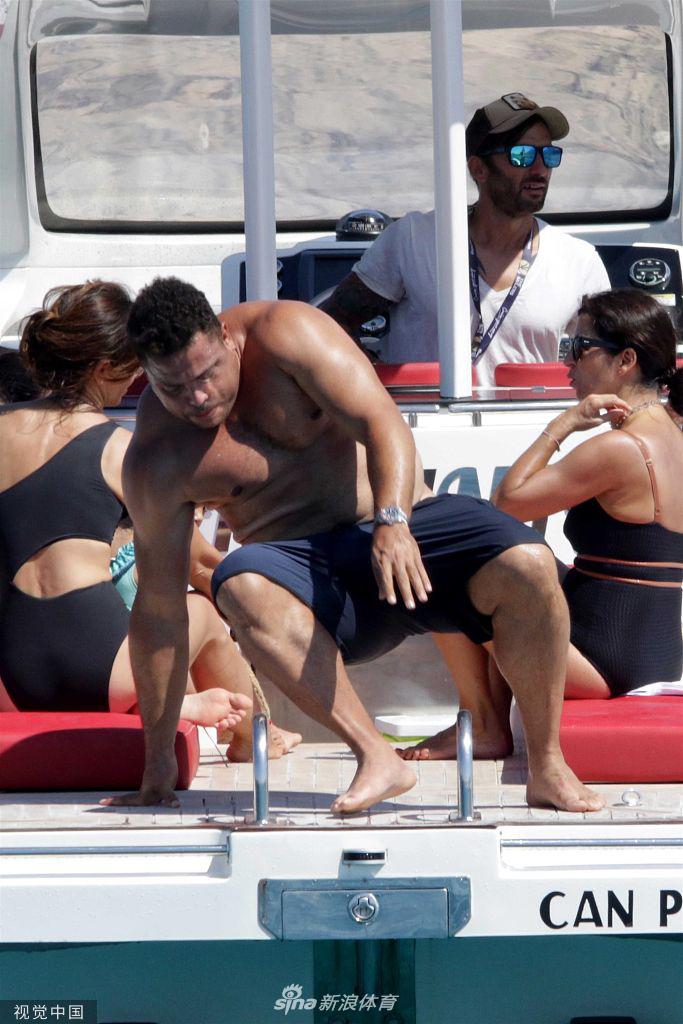 大罗站在游艇的楼梯上，准备下水或上船，这个瞬间他的肚子显得格外圆滚滚，但同时也展示了他粗壮有力的大腿，毕竟这是当年支撑他风驰电掣的基础