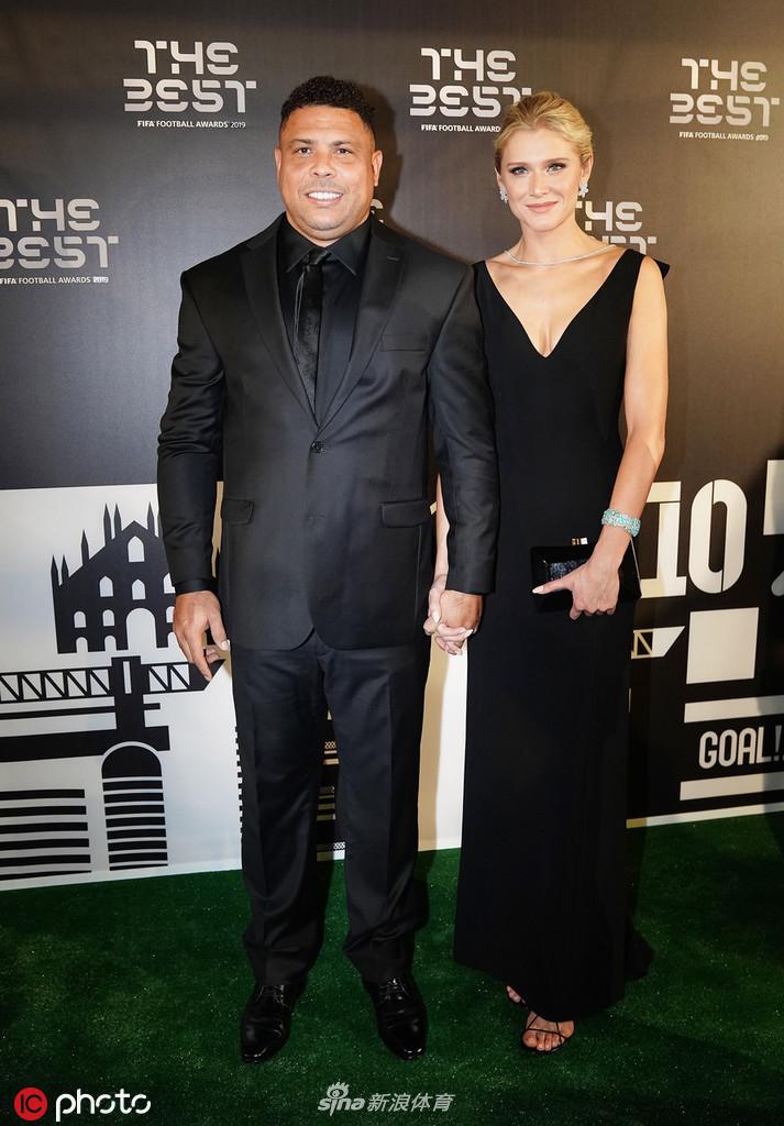 大罗与女伴在签名板前合影，他一手轻揽女伴的腰，两人对着镜头露出迷人的微笑，将这美好的瞬间定格在2019年的米兰之夜。