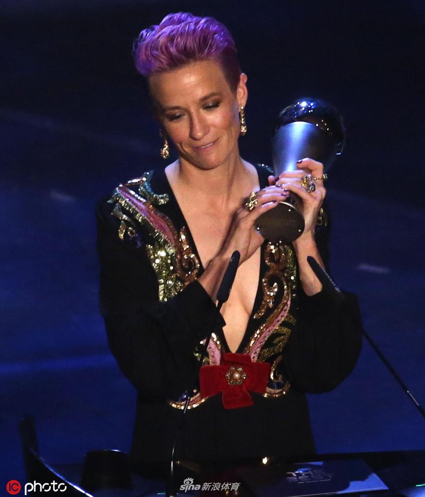 梅根·拉皮诺埃身着一袭优雅长裙，手捧金光熠熠的世界足球小姐奖杯，在米兰斯卡拉剧院的聚光灯下展露自信而迷人的微笑，这一刻的荣耀属于她也属于整个美国女足。