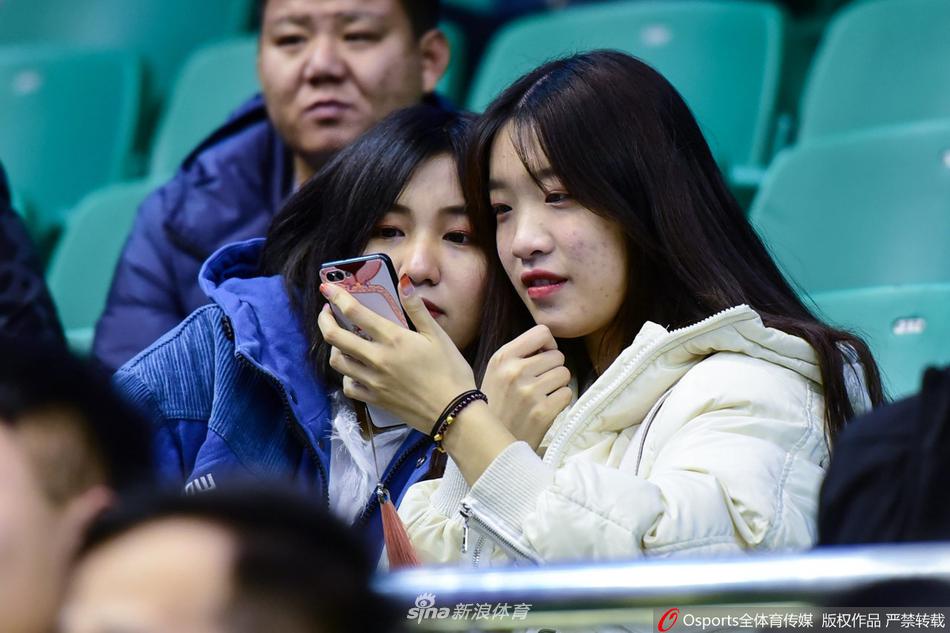 一位长发披肩的女球迷面带温柔的笑容，她轻轻撩起垂落的一缕发丝，眼神中闪烁着对胜利的坚定渴望，那份从容与美丽在激烈的赛场边显得格外动人。