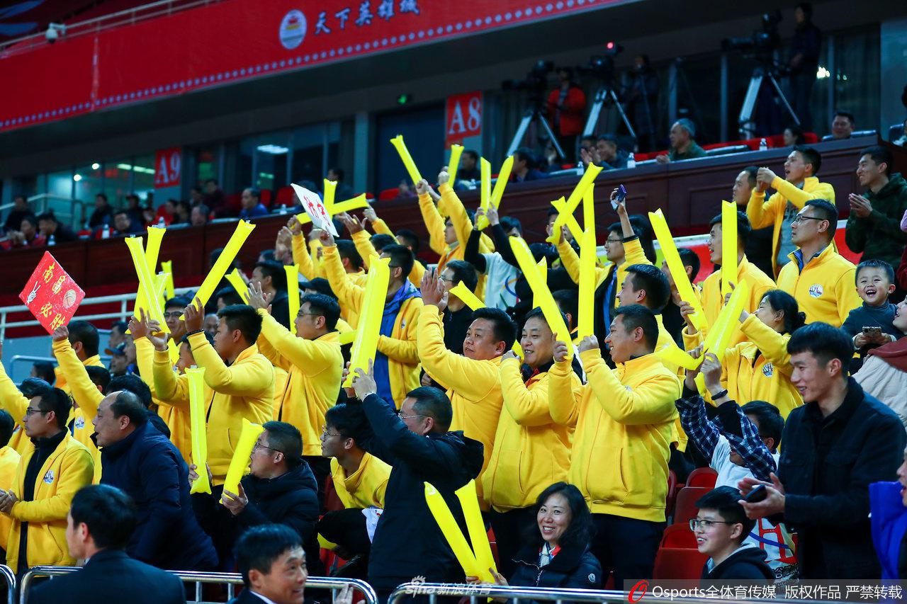 看台上，几位年轻球迷激动地振臂高呼，他们的脸上写满了紧张与兴奋，身后的助威标语在灯光下显得格外醒目。