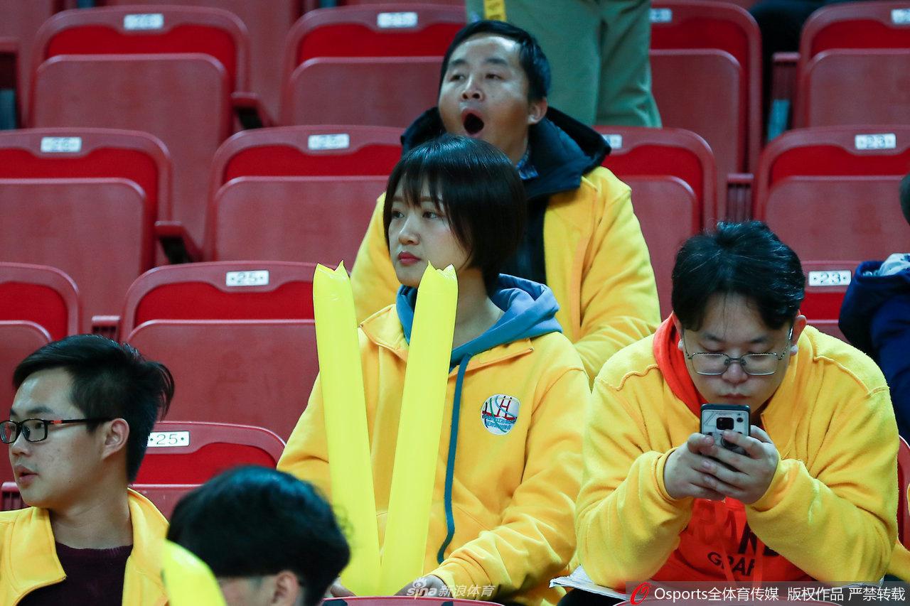 一对情侣球迷脸上贴着八一队的贴纸，女生开心地对着镜头比出剪刀手，男生则憨厚地笑着，他们的幸福与赛场的激情融为一体。