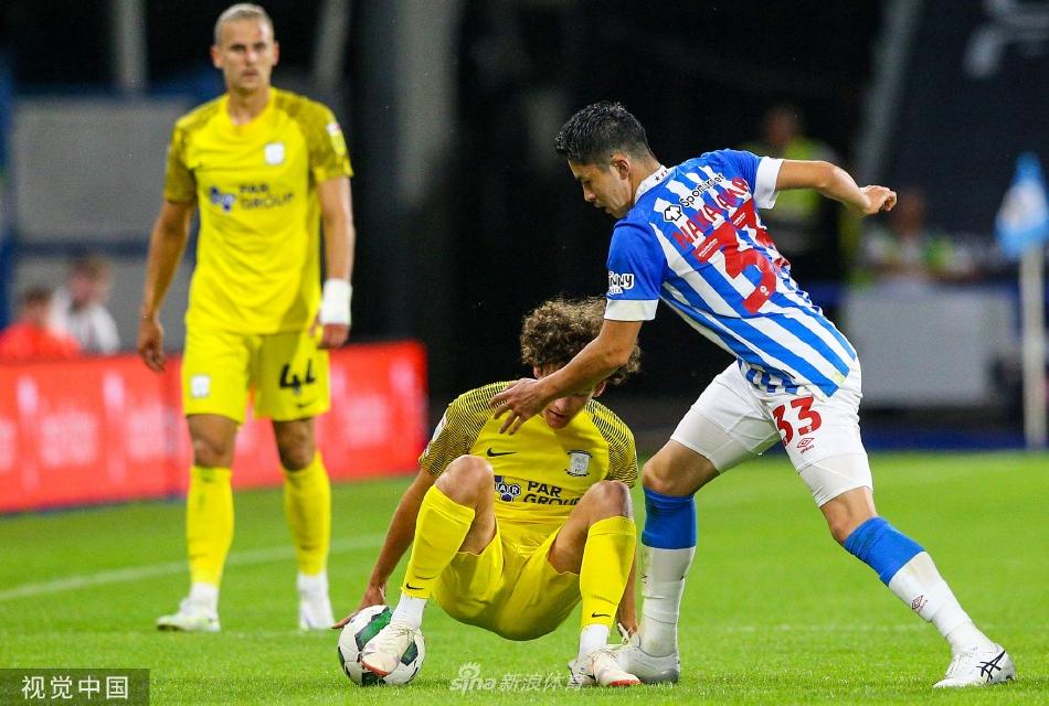 普雷斯顿球员阿里斯泰尔·麦卡恩梅开二度后与队友激动相拥，背景是记分牌上刺眼的比分