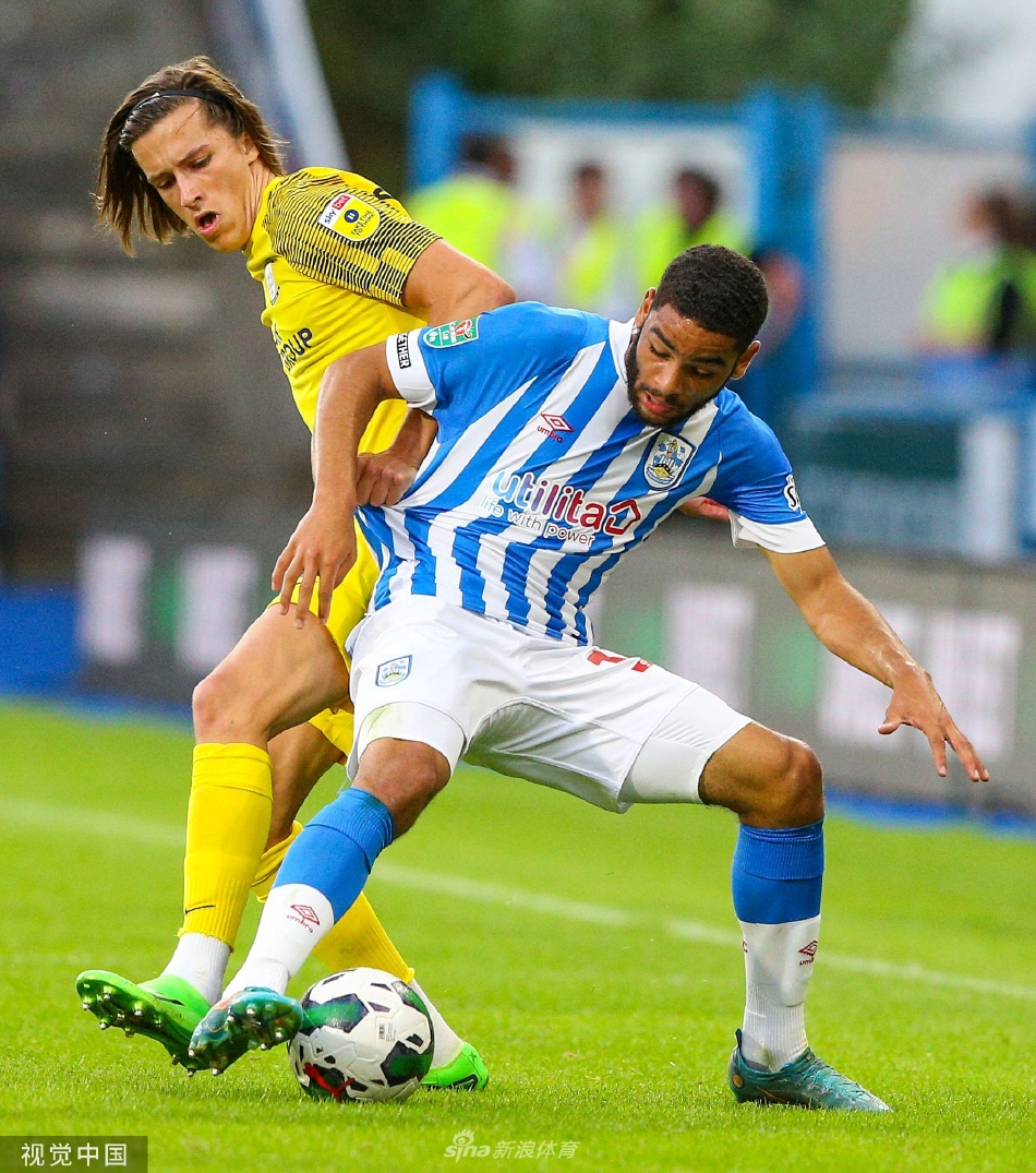 普雷斯顿球员特洛伊·帕罗特破门后张开双臂奔跑庆祝，背后是垂头丧气的哈镇后卫