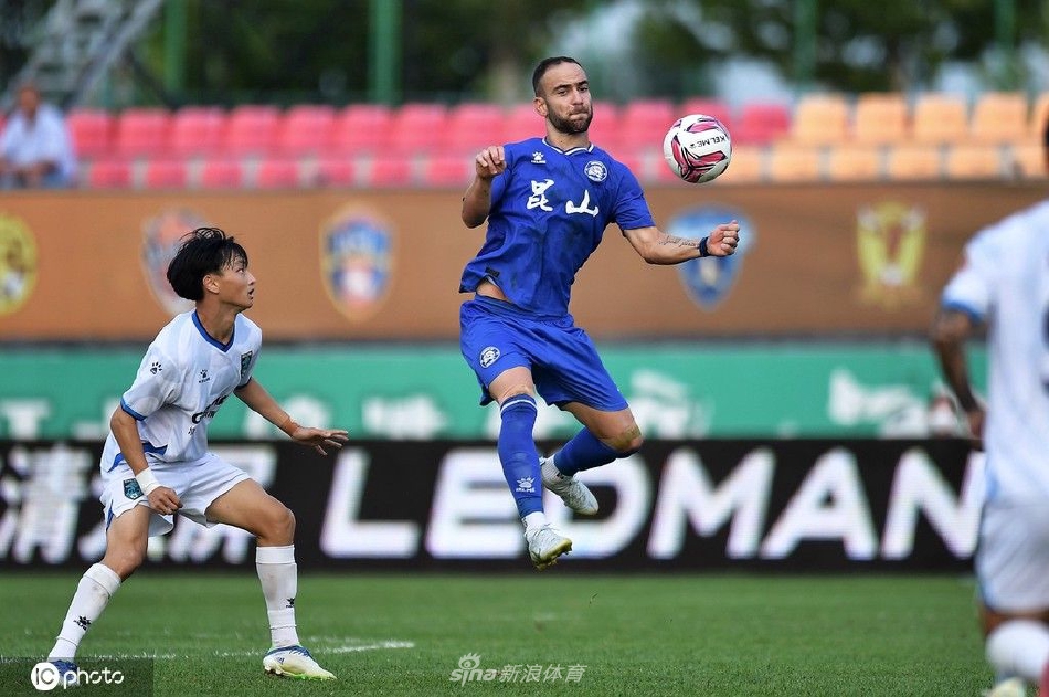 在河北唐山的绿茵场上，昆山与南通支云的球员们正在进行一场激烈的江苏德比，画面定格在双方中场拼抢的瞬间，空气中弥漫着榜首大战的紧张气息。