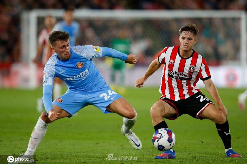 谢菲联主教练在场边紧握双拳激情呐喊，指挥球队防守，身后替补席上的队员们也紧张地关注着场上局势。