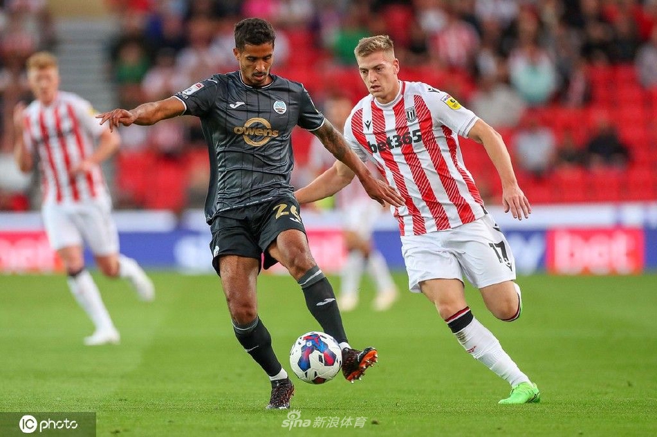 斯旺西球员带球突破，面对两名防守球员的包夹，他神情专注，脚下技术细腻，正寻求突破或分球的空间。