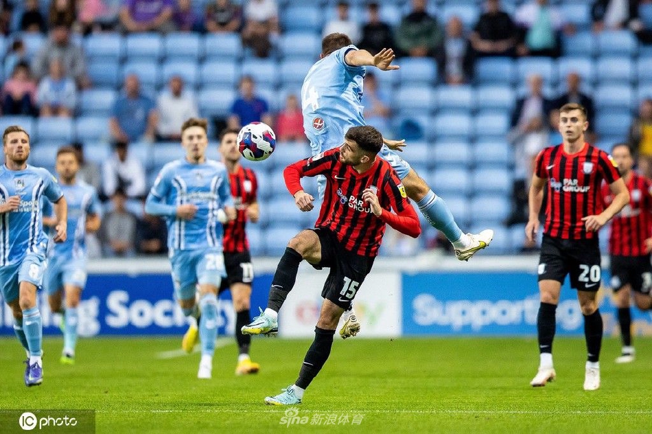 比赛激烈拼抢瞬间，考文垂中场球员与普雷斯顿对手同时伸脚争夺球权，草屑飞溅。