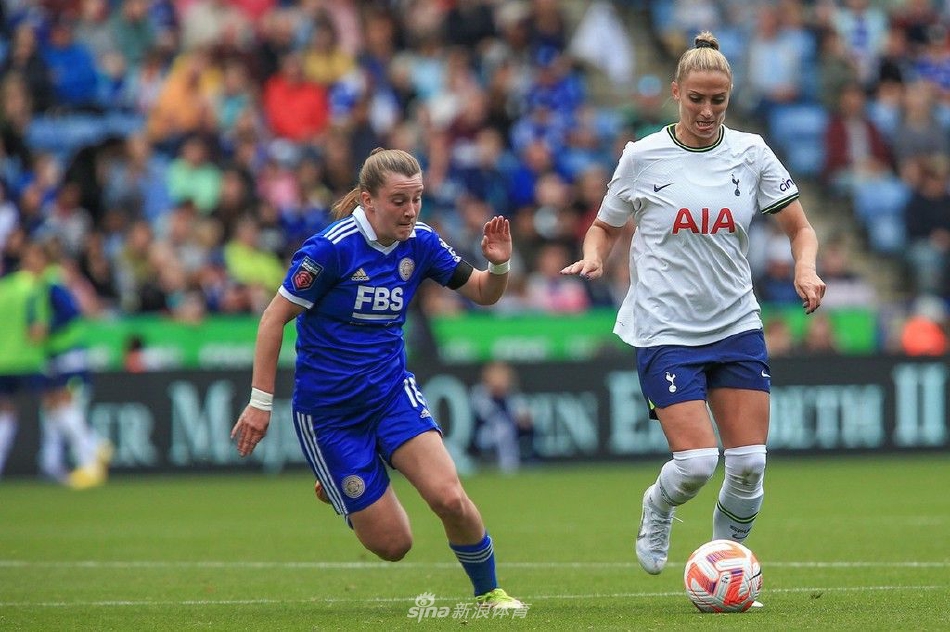 热刺女足球员在防守中精准滑铲，成功将球破坏出边线，草屑随之飞扬，动作干净利落。