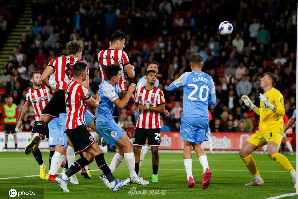 布拉莫巷体育场座无虚席，谢菲联球员带球突破桑德兰防守球员，球迷看台上旗帜飘扬，气氛热烈。