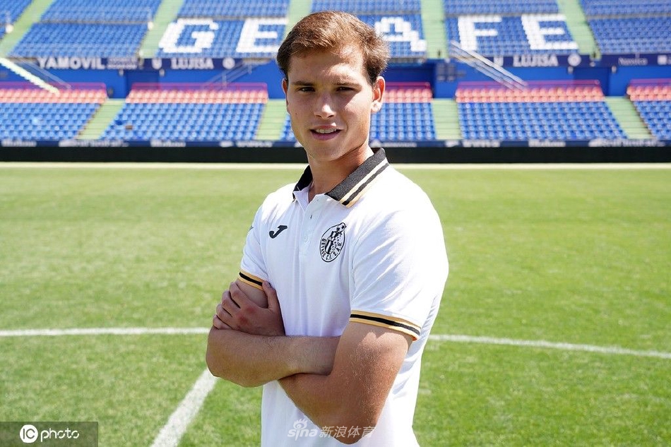 拉塔萨与赫塔菲队徽合影，神情坚定，眼中充满了对新挑战的期待与决心