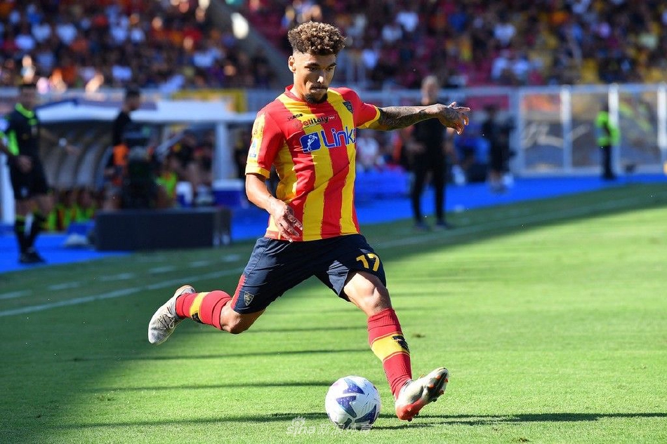 莱切队球员与蒙扎队球员在中场展开激烈拼抢，双方身体对抗激烈，球鞋带起的草屑清晰可见