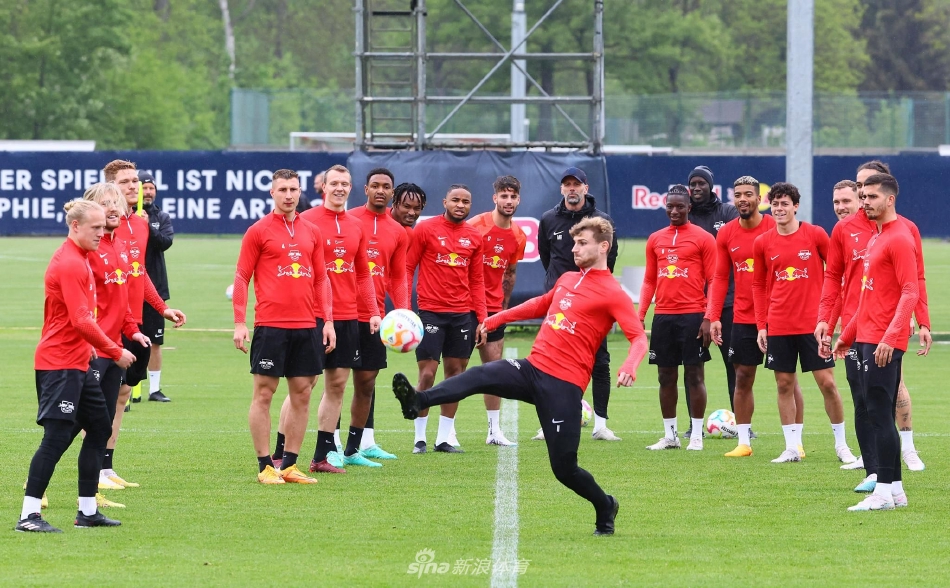 莱比锡主帅马尔科·罗泽正在训练场边凝神布置战术，他手中的战术板与坚定的眼神透露出对比赛的深思熟虑。