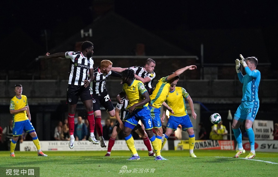 主裁判在双方球员包围中指向中圈，确认进球有效，场面紧张而充满戏剧性