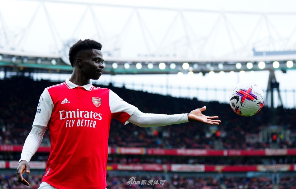 萨卡与阿森纳名宿或俱乐部官员并肩而立，手指俱乐部徽章，眼神中充满对未来的承诺与归属感