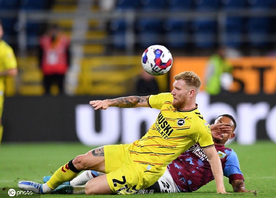 看台上小球迷骑在父亲肩头挥舞旗帜，眼中闪烁着对足球最纯真的热爱与向往