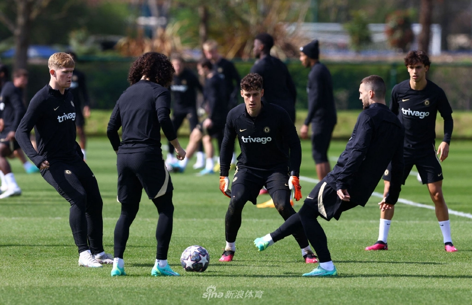 主教练兰帕德立于训练场中央，双臂交叉于胸前，目光如炬地凝视着场上球员的战术演练，身后是科巴姆基地整齐的绿茵与训练设施。