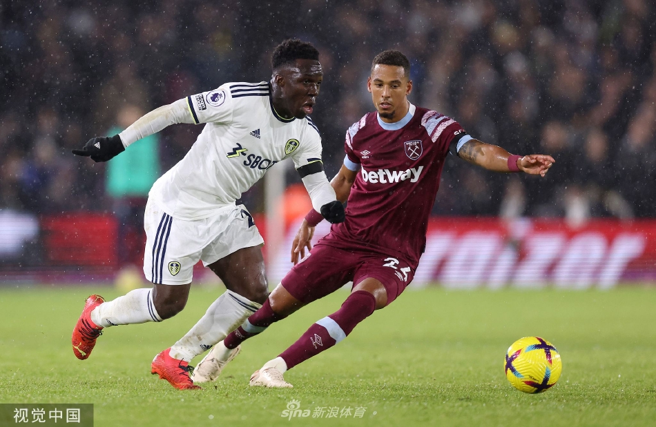 利兹联前锋带球突破，对方后卫奋力回追，画面充满速度与力量的对决，草屑在鞋钉下飞扬。