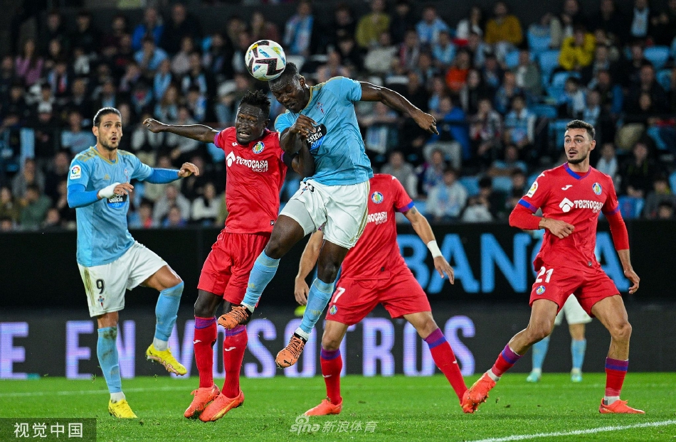 双方中场球员在中圈附近展开激烈拼抢，四目相对互不相让，飞扬的草屑与紧绷的肌肉尽显对抗的激烈程度。