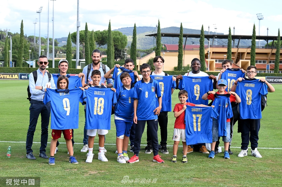 全队球员与来访的小球迷们拍摄大合影，孩子们手持球队围巾笑容灿烂，队伍气氛融洽