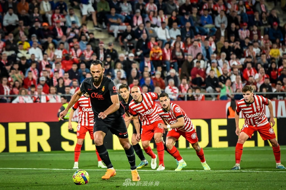 马洛卡球员主罚任意球瞬间，人墙高高跃起试图封堵射门路线，皮球如出膛炮弹般穿越人群飞向球门左上角