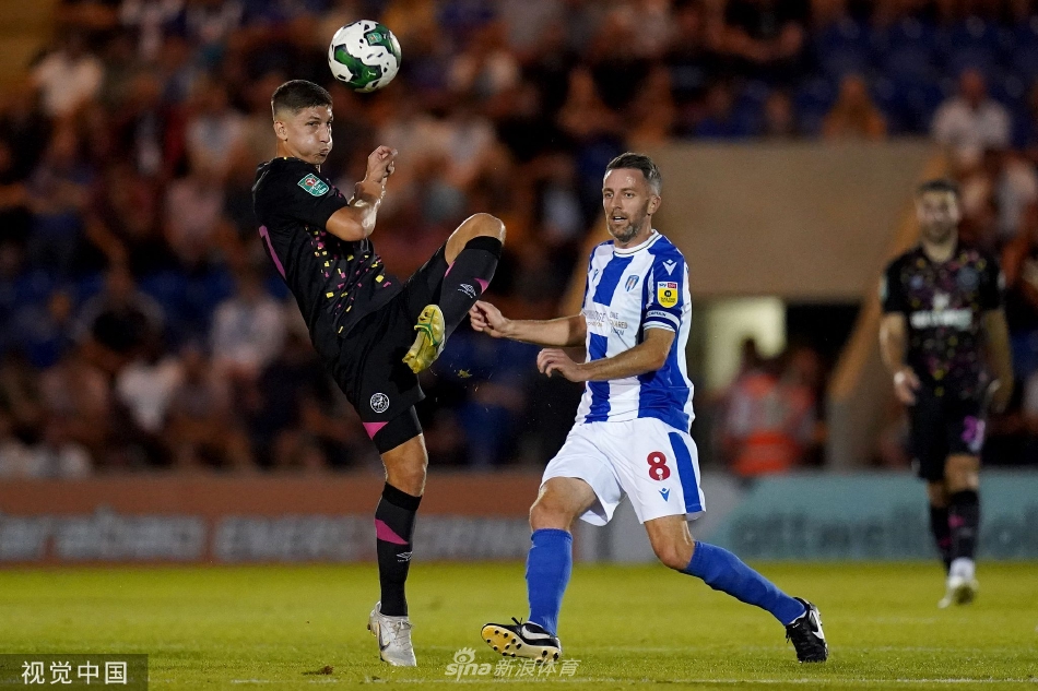 比赛间隙，科切斯特联的主教练在场边神情专注，向场内球员大声呼喊并比划手势，紧急部署新的战术安排。