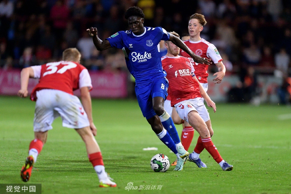 弗利特伍德中场球员在中场与埃弗顿球星进行激烈拼抢，草屑飞溅，两人身体对抗的瞬间展现了杯赛毫不保留的拼搏精神。