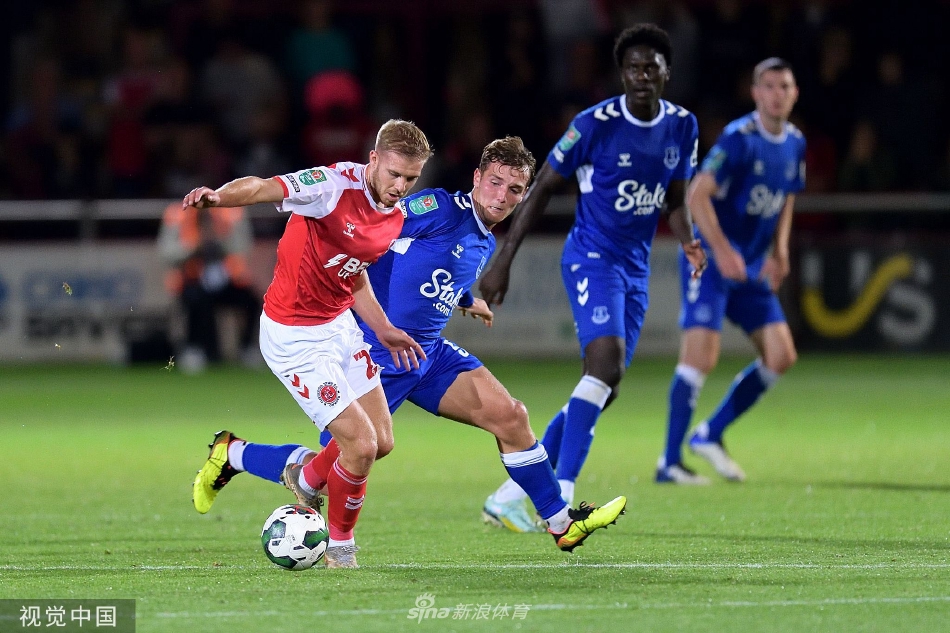 高天球场灯火通明，看台上红色的弗利特伍德球迷海洋与绿色的草坪形成鲜明对比，夜空下充满了大战将至的紧张与期待。