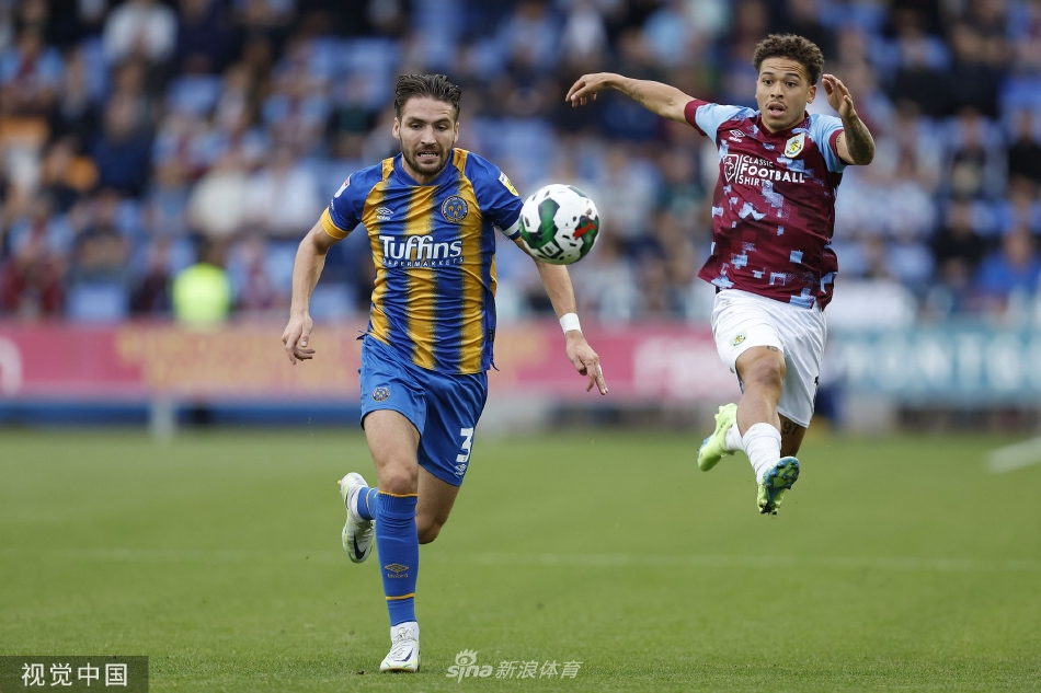 比赛开场，伯恩利球员在中场积极拼抢，身穿紫色客场球衣的队员正用一记精准滑铲破坏对方进攻