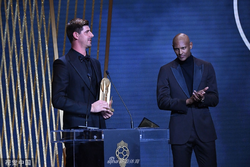 库尔图瓦凝视着手中的雅辛奖杯，眼神专注，仿佛在回顾过去一个赛季那些至关重要的扑救瞬间。