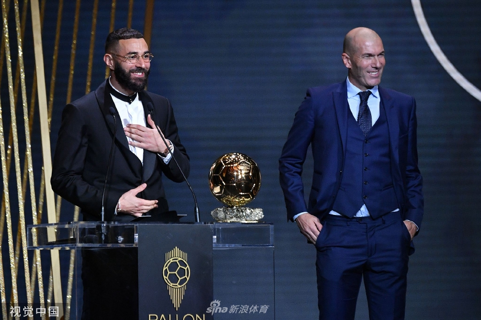 本泽马在领奖台上深情凝视奖杯，指尖轻触金球，仿佛在触摸无数个日夜奋斗的梦想