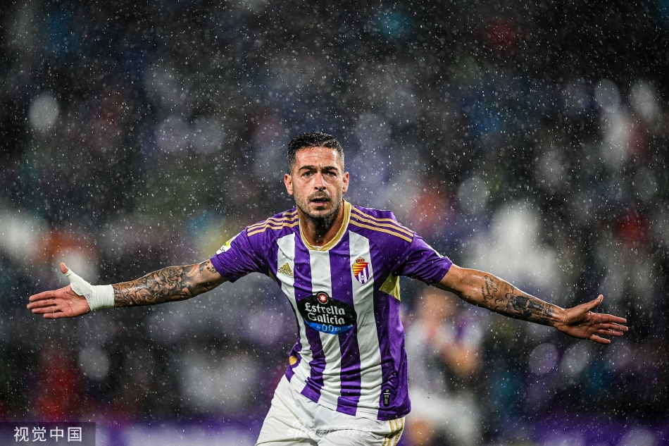 巴拉多利德球员进球后狂奔至角旗区滑跪庆祝，双臂张开仰天长啸，身后是蜂拥而至激动万分的队友。