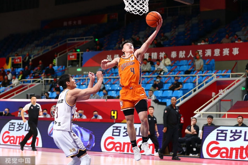 上海队球员闫鹏飞在篮下高高跃起，伸出长臂，奋力封盖北控球员廖三宁的上篮，防守气势十足