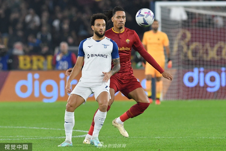 拉齐奥全队围拥庆祝进球，蓝色身影在罗马主场激情绽放，背景中红衣罗马球员黯然神伤。