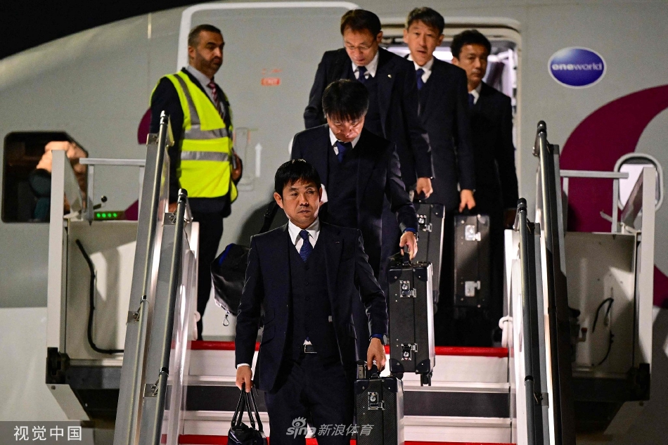 队长吉田麻也正在与工作人员交流，他手指前方，沉稳地安排着事宜，展现出领袖的担当与风范。