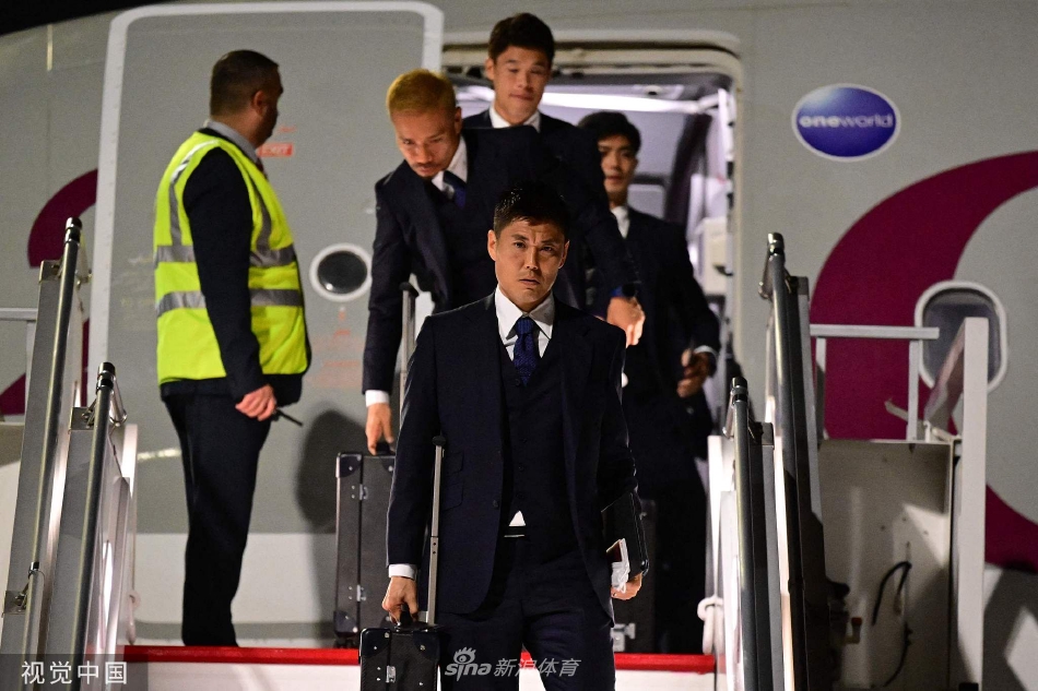 日本队球员们有序地走在机场廊桥上，统一的深蓝色西装显得队伍整齐划一，年轻球员的脸上写满了对世界杯的憧憬。