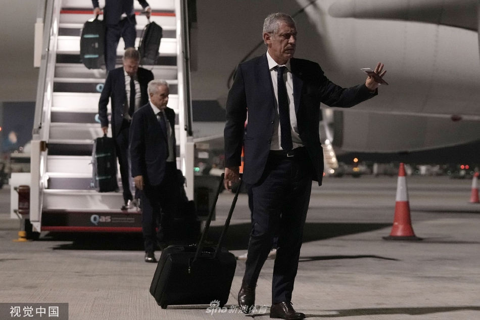 全景视角下，葡萄牙国家队成员们陆续登上印有世界杯标识的专用大巴，大巴车灯照亮了夜幕，象征着征程的启航