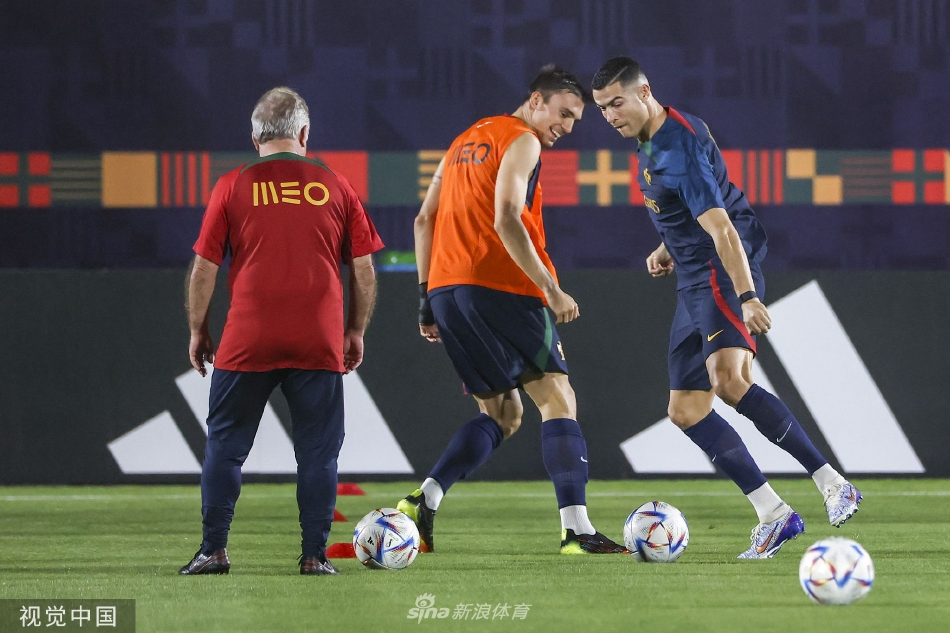 训练间隙球员们在场边补水交流，背景是卡塔尔独具特色的现代建筑天际线