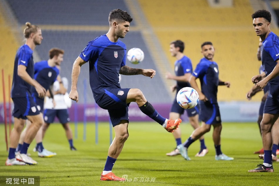 美国队主教练格雷格·伯哈尔特神情专注，正在场边与助理教练团队仔细研究战术板，谋划对阵英格兰的关键策略。