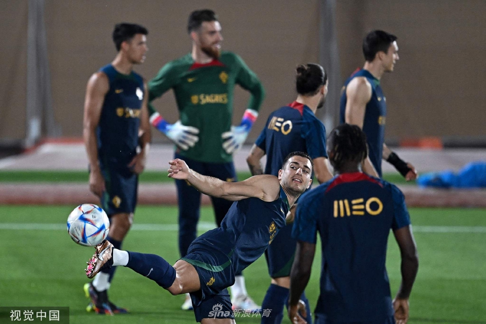 球员们在训练中进行分组对抗，绿色草地上身影交错，足球在空中划出优美弧线