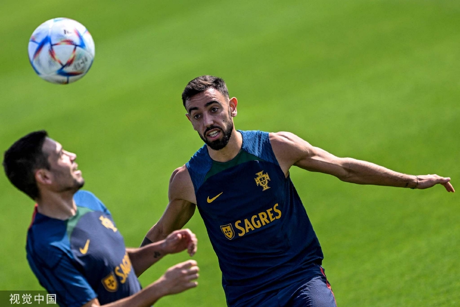 训练场上，葡萄牙队员们分散进行着有球练习，背景是卡塔尔标志性的现代建筑，蓝天白云下洋溢着专注与活力