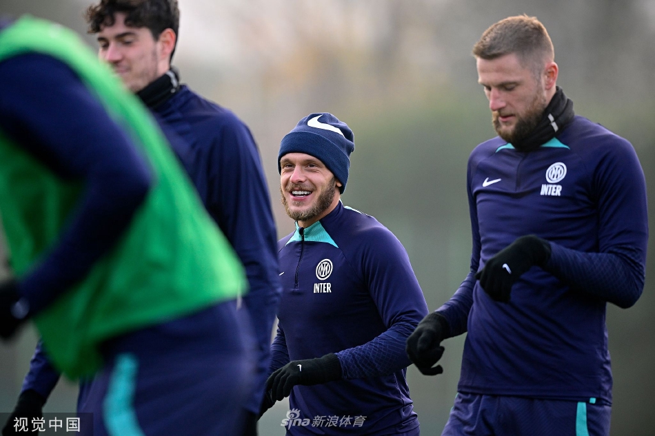 训练间隙，两名球员并肩行走交流心得，阳光将他们的身影拉长在绿茵场上