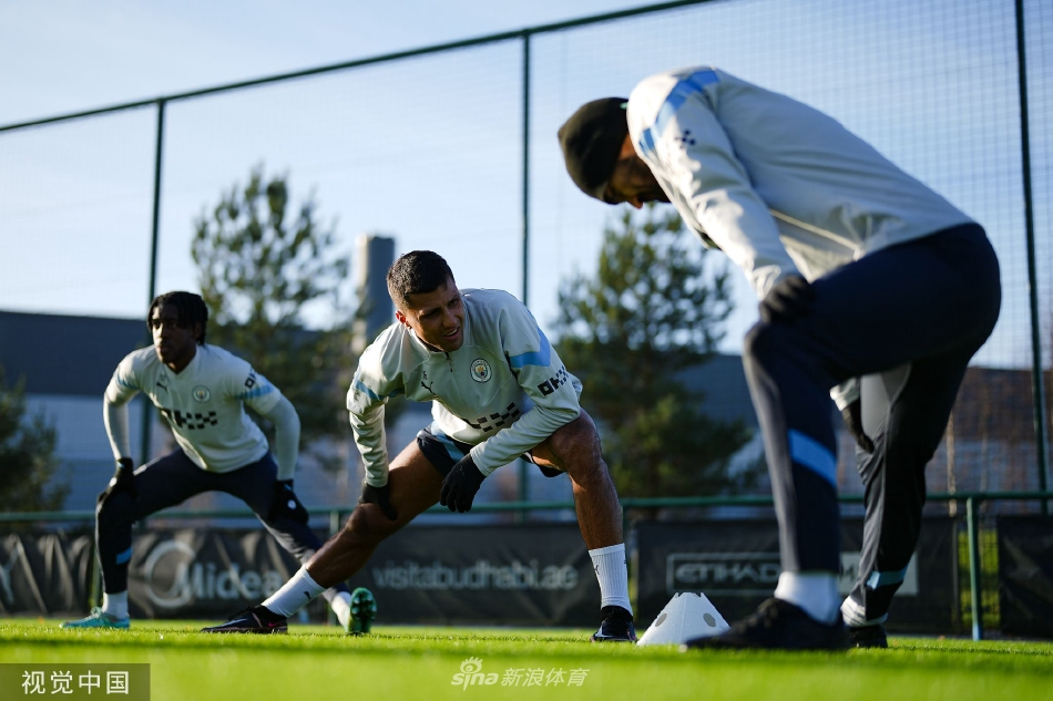 训练间隙,两名曼城球员坐在草地上一边放松一边交流,脸上带着笑容,展现了更衣室内的良好氛围与队友情谊。