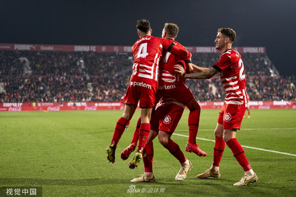 比赛结束后，双方球员交换球衣，彼此拍肩致意，背景是逐渐散去的球迷看台