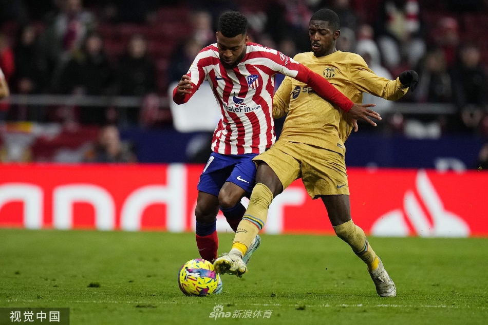 马竞前锋在巴萨禁区混战中奋力争顶，皮球划空而过，双方球员肌肉碰撞、寸土不让，场面极具张力与对抗性。