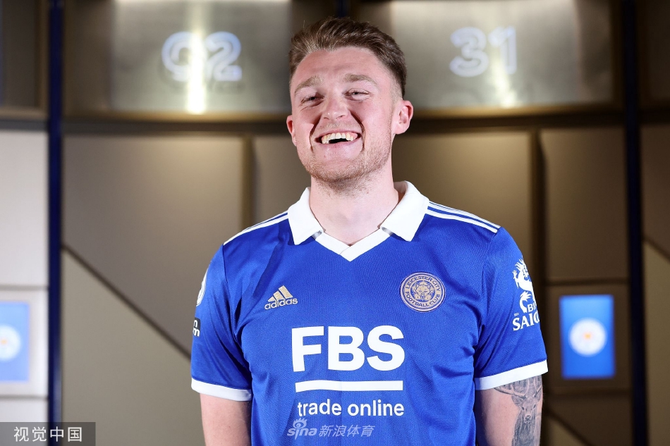 苏塔与俱乐部官员握手致意，桌上摆放着印有他名字的蓝色球衣，象征着正式协议的达成。