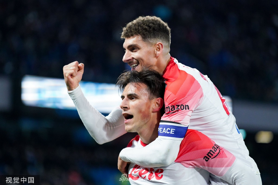 克瓦拉茨赫利亚进球后滑跪庆祝，身后是狂热的那不勒斯南看台和漫天飞舞的蓝色彩带