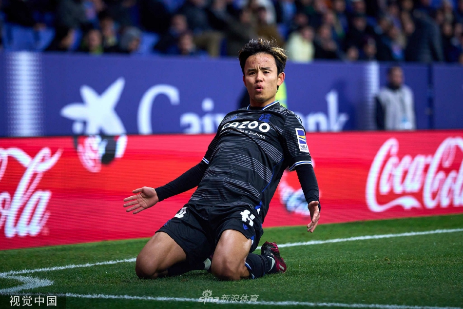 皇家社会球员围拢在一起激情庆祝进球，背景中西班牙人门将神情沮丧。